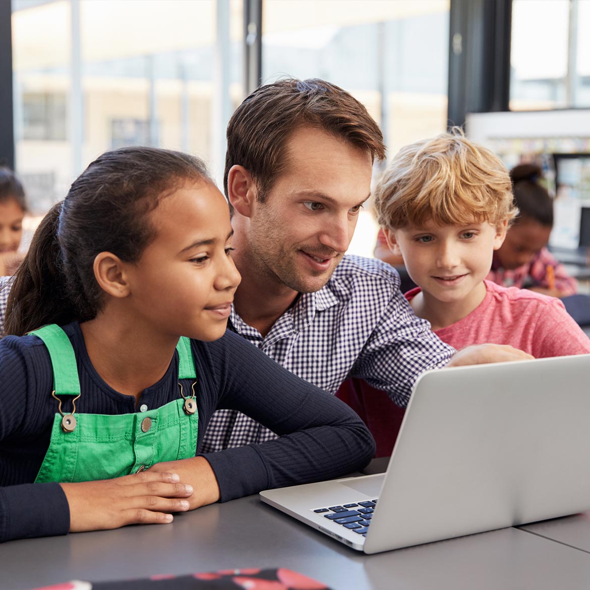 Teacher explaining concept on laptop to students