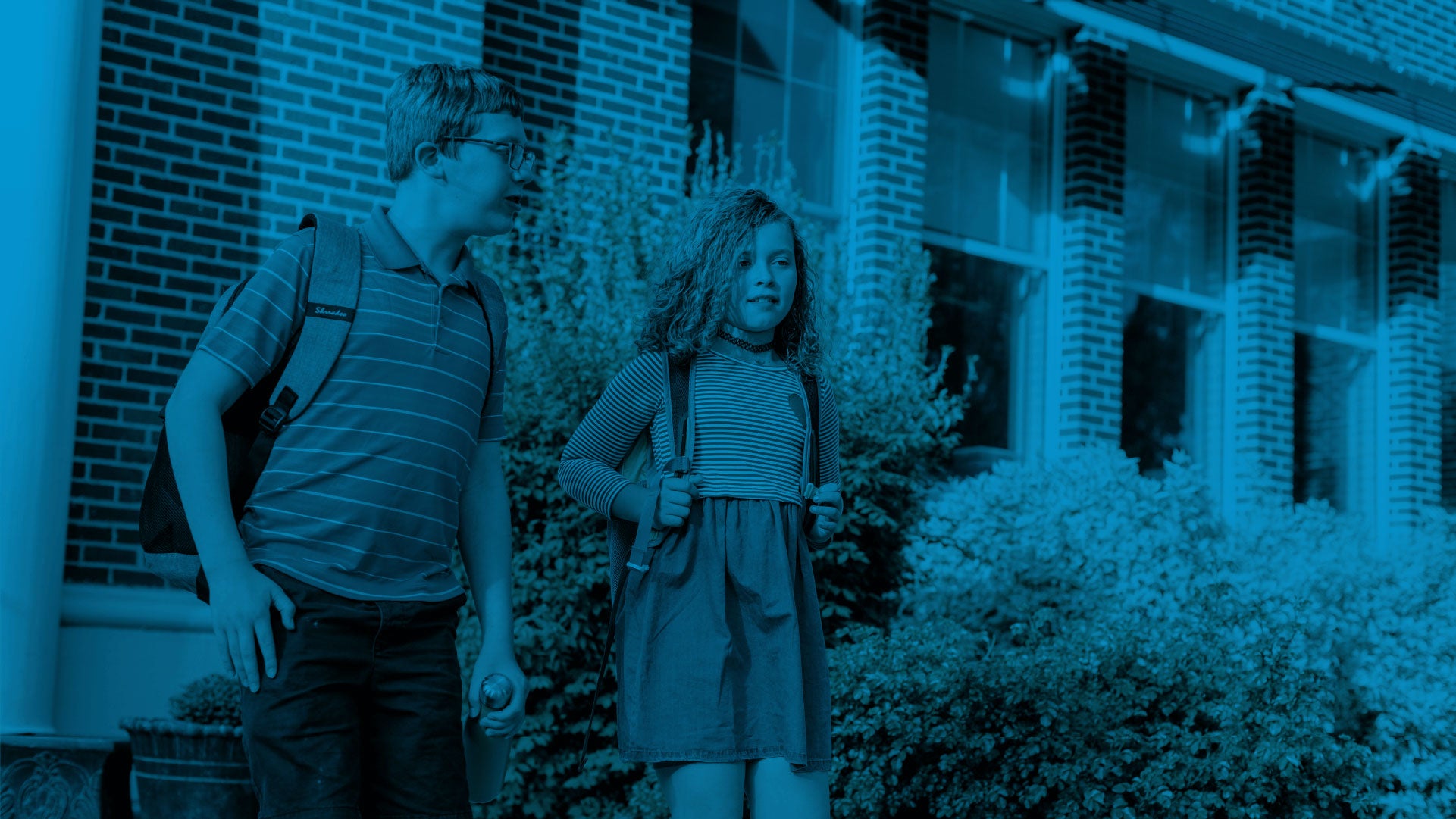 Two students wearing a backpack on school
