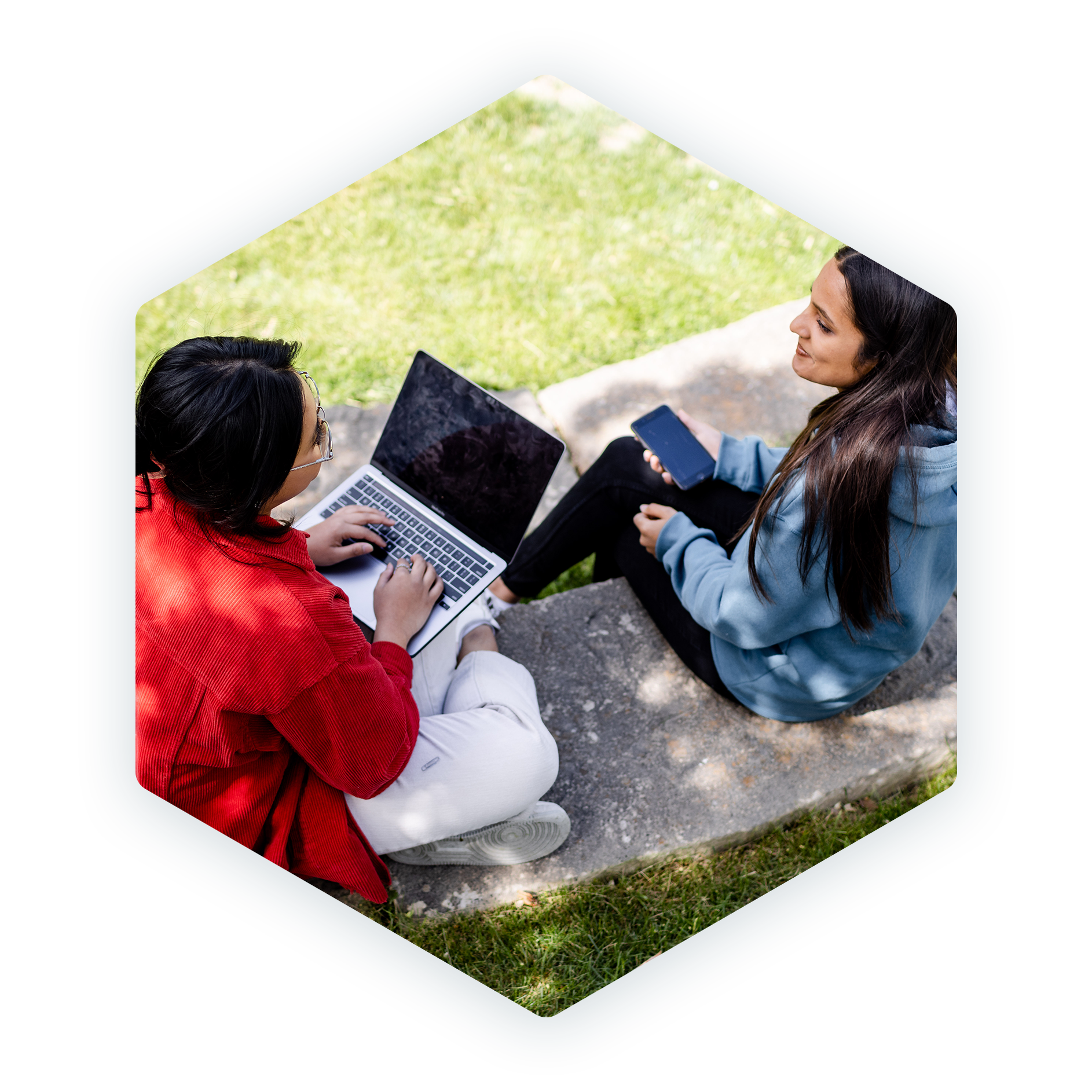 Two students using a laptop and a phone