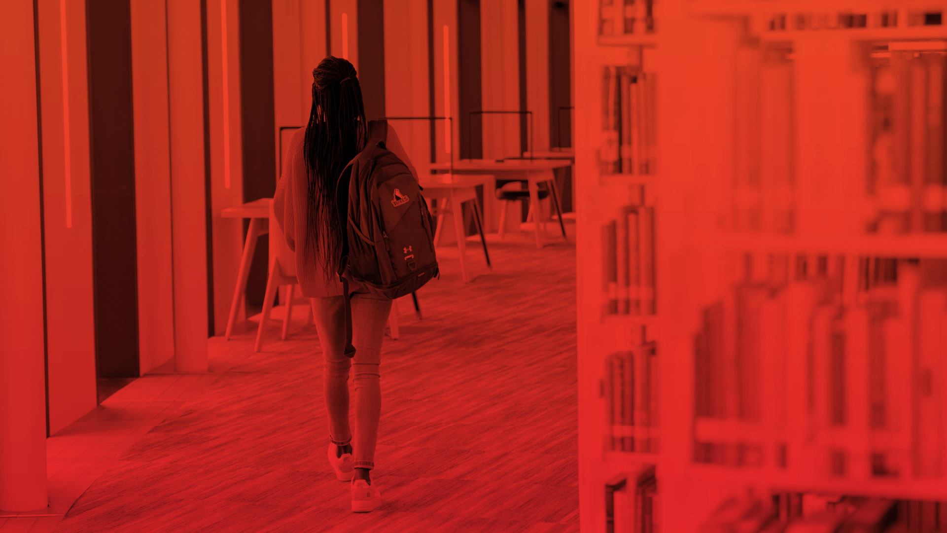 A woman wearing a backpack while walking in the library