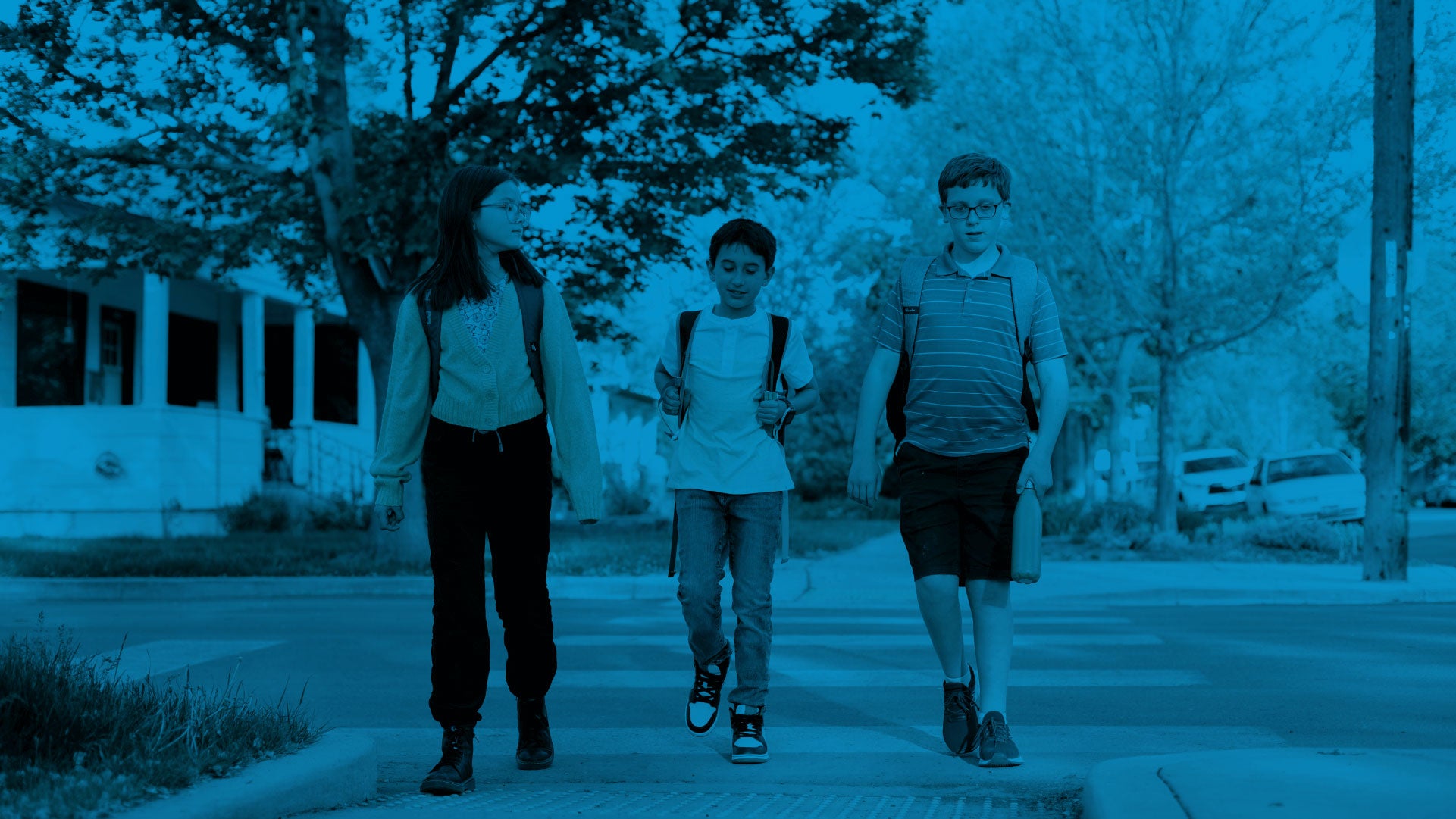 Students wearing a backpack while crossing the pedestrian lane