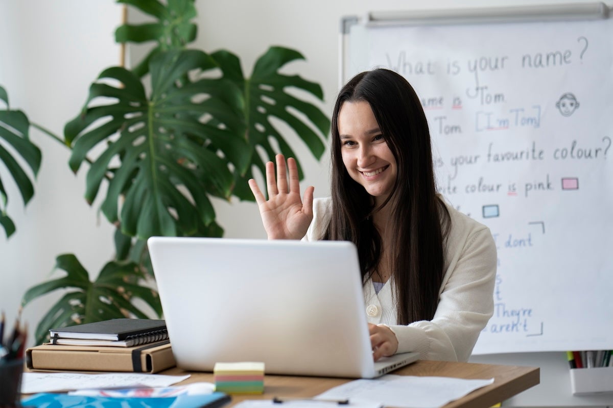woman smiles while watching and interacting with laptop