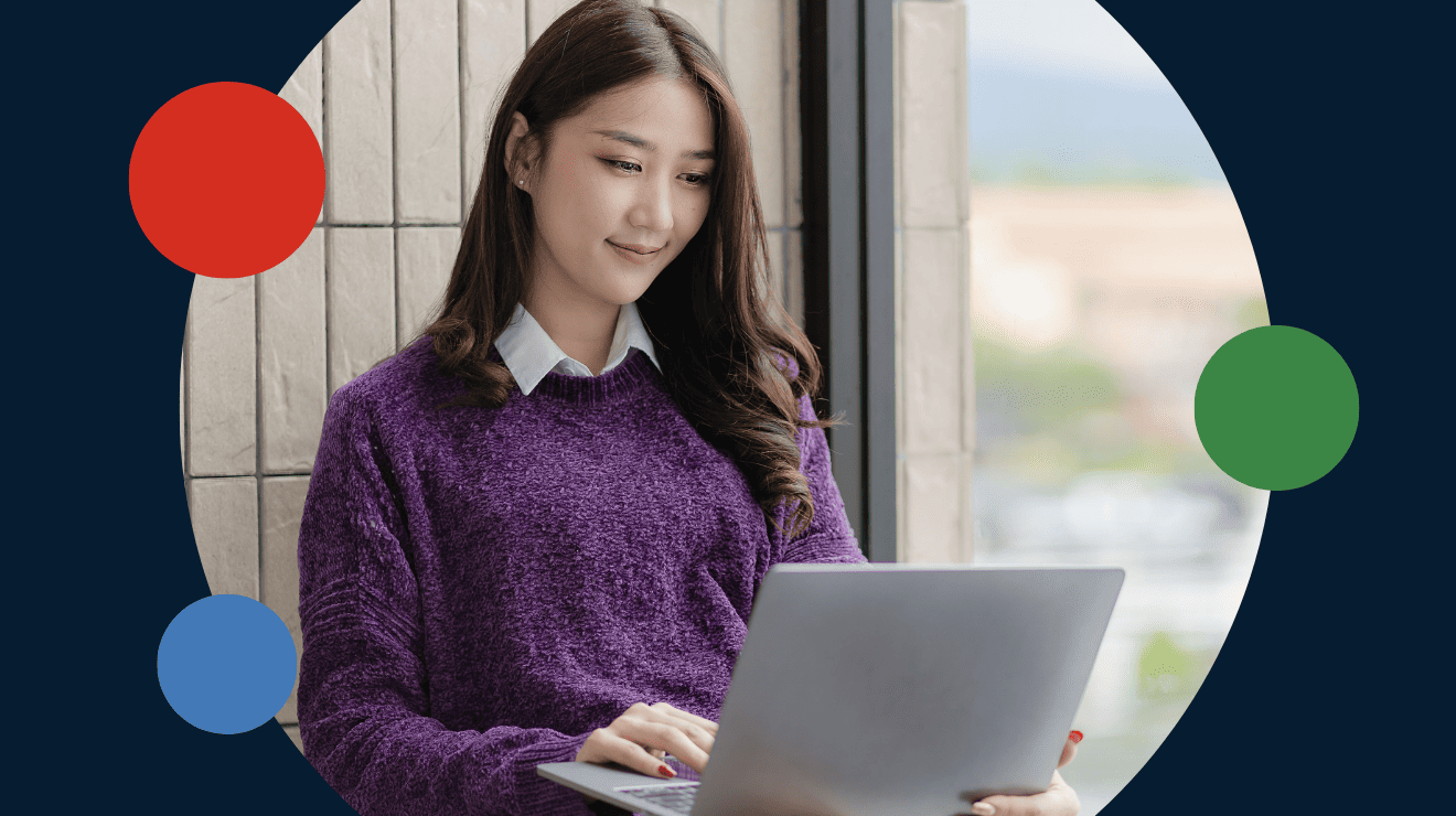 A woman in a chair, engaged with her laptop, surrounded by a simple, uncluttered environment.