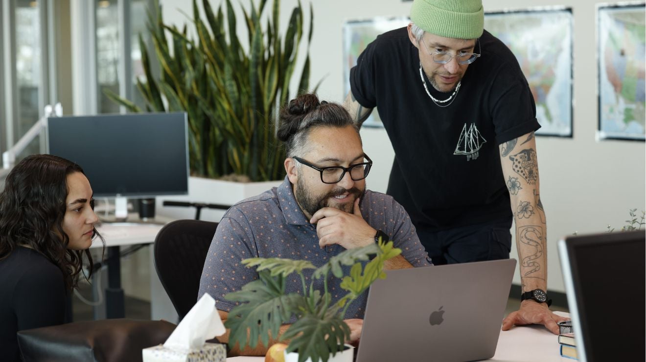 Team reviewing content together on a laptop in an office.