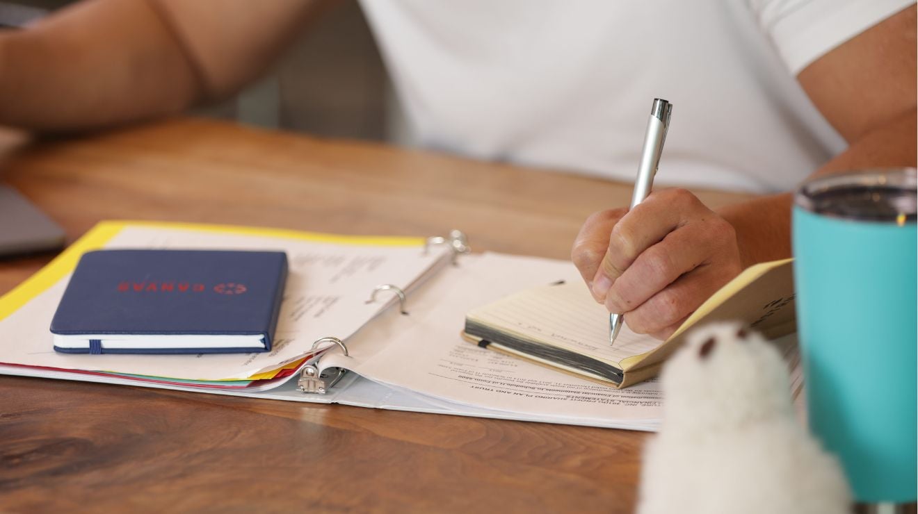 Close-up of hands writing in a notebook with Canvas branding.