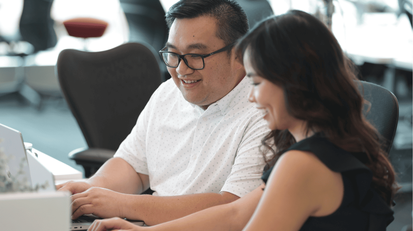 woman and man smiling while using laptop