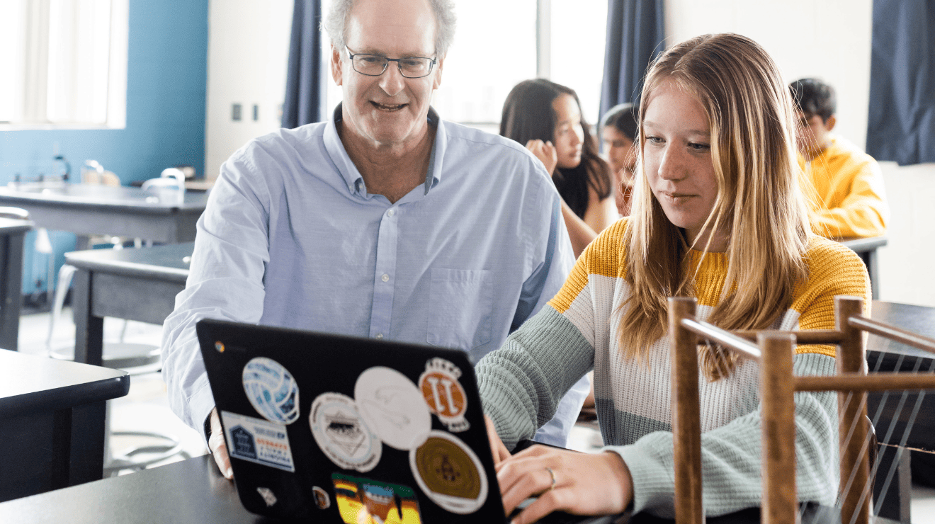 A man and a young woman are looking at a laptop