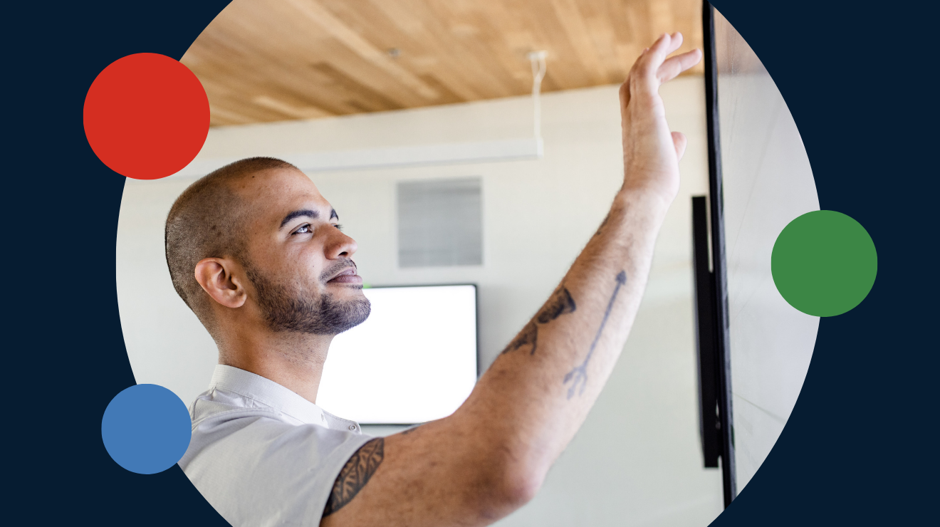  A man reaches up to touch a wall where a television is mounted, appearing curious about the screen.