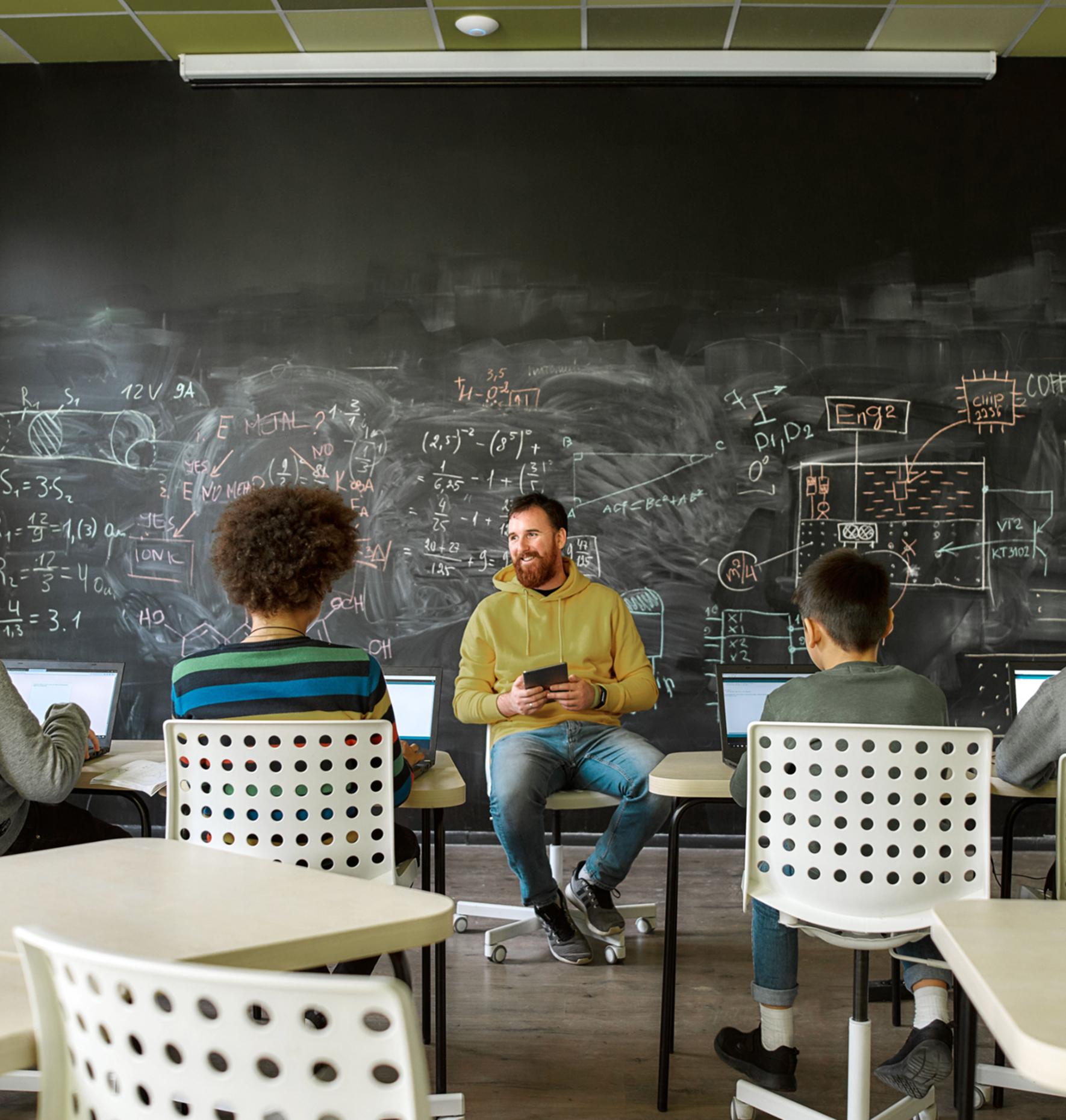 A teacher and students conversing in front of a blackboard