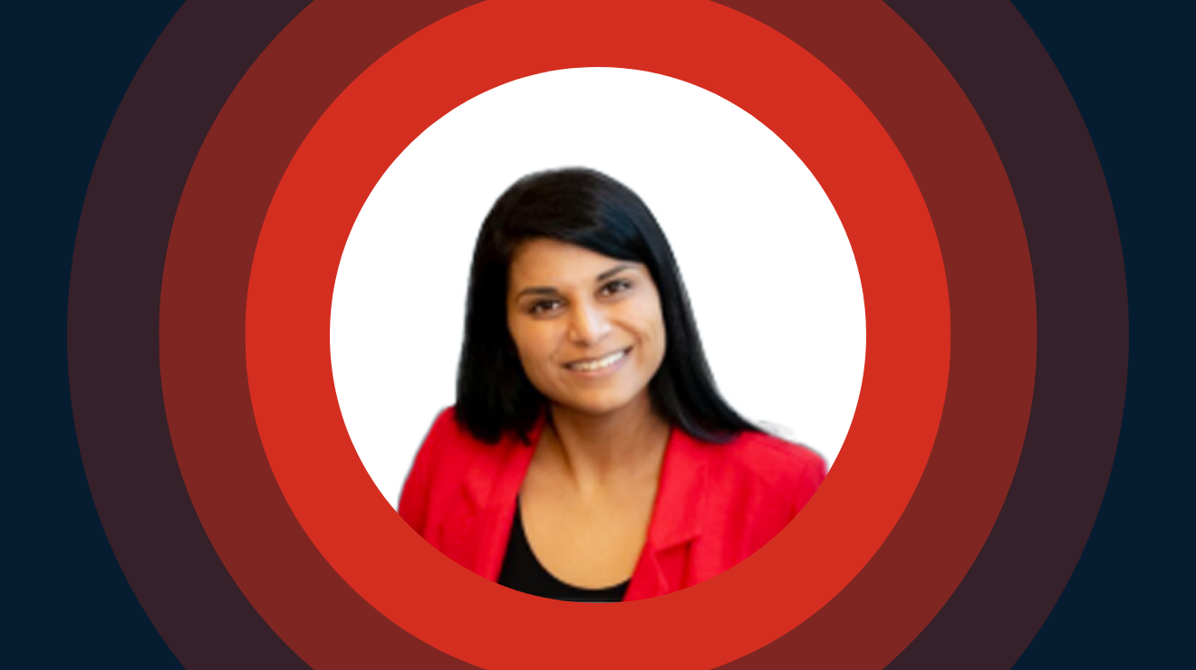 A smiling woman wearing a red jacket stands against a neutral background.