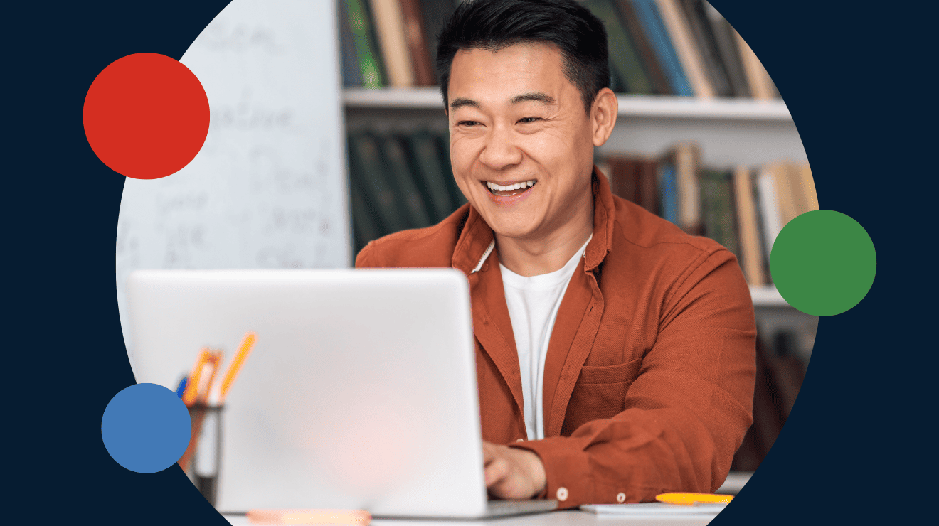 A man smiling while using a laptop, conveying a sense of enjoyment and engagement with his work or leisure activity.