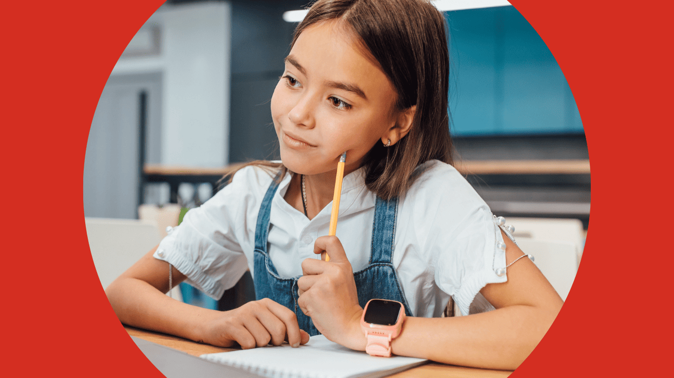 A girl sitting at a desk, holding a pencil, focused on her work.