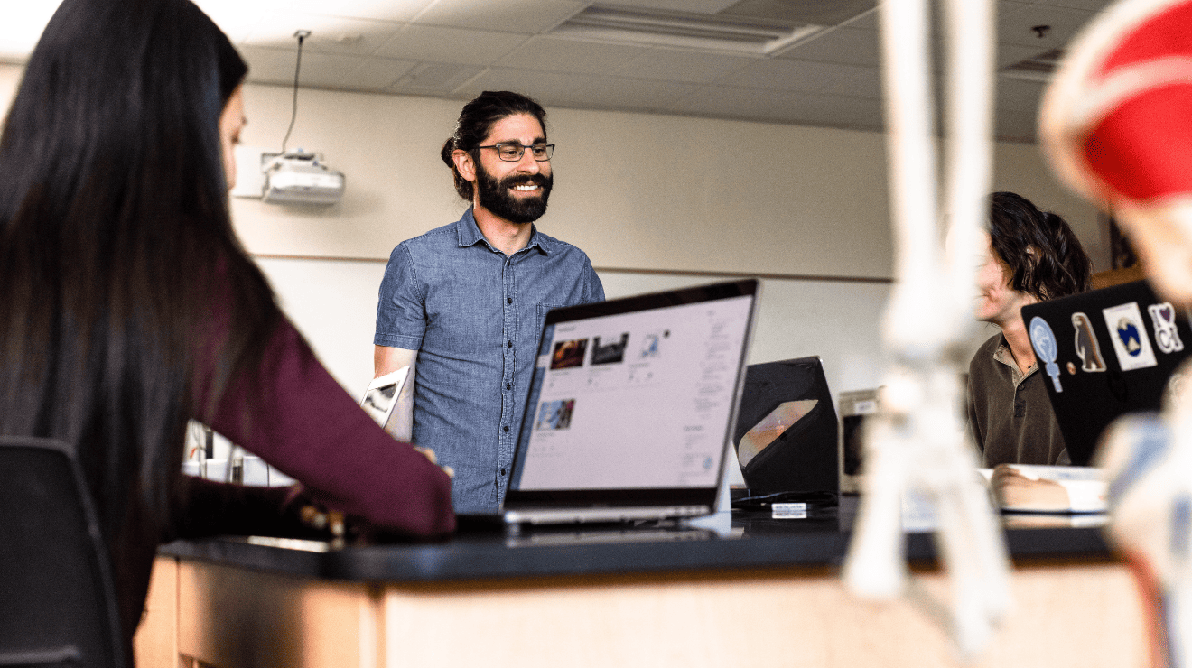  A man and woman sit in a classroom, focused on a laptop in front of them, engaged in a learning activity.