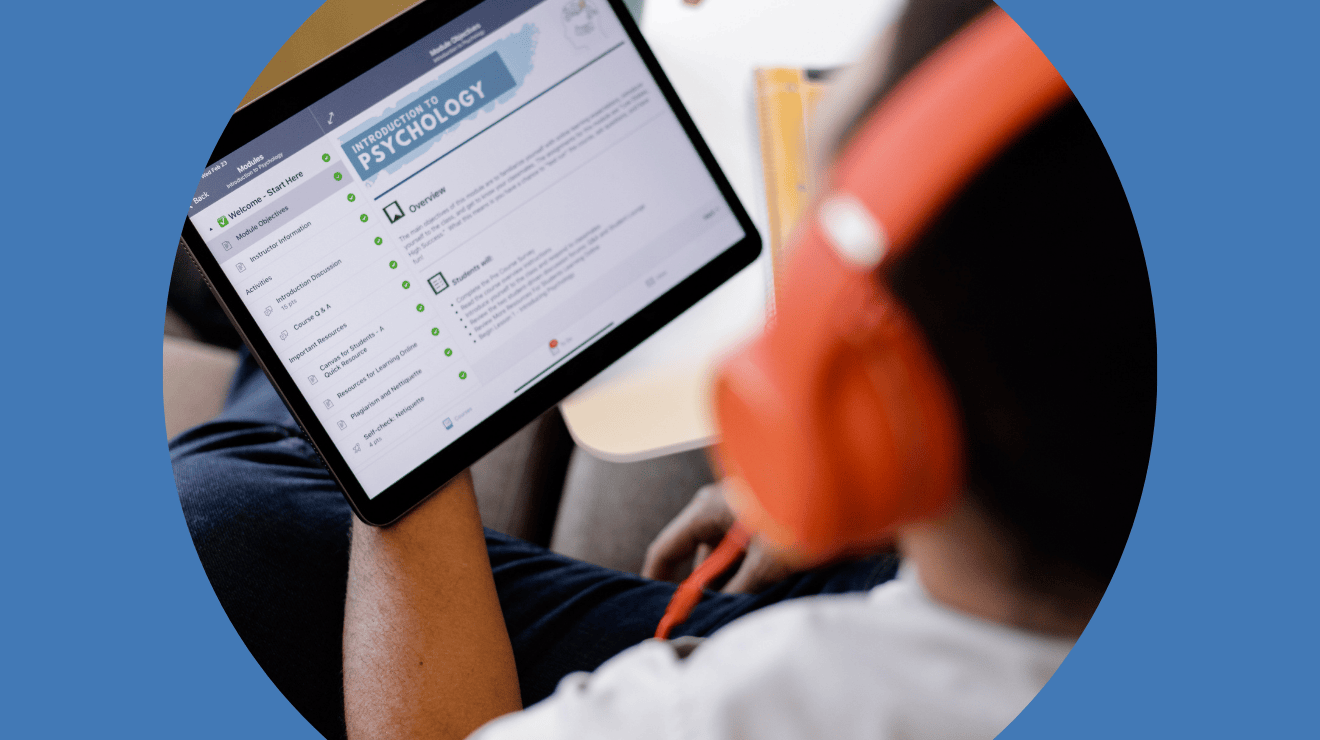 A uni student with headphones looks at a tablet with a Canvas course loaded onto the screen
