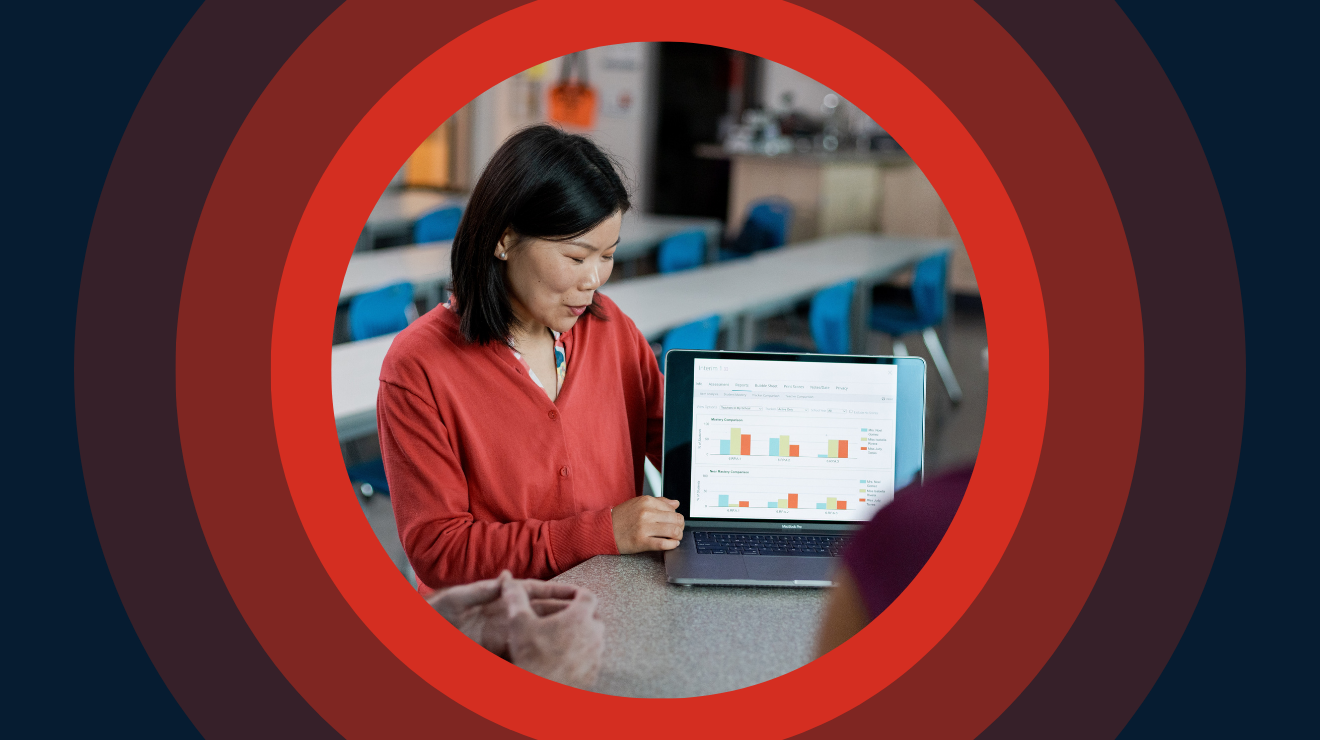 Woman in red blouse sits at table with an open laptop