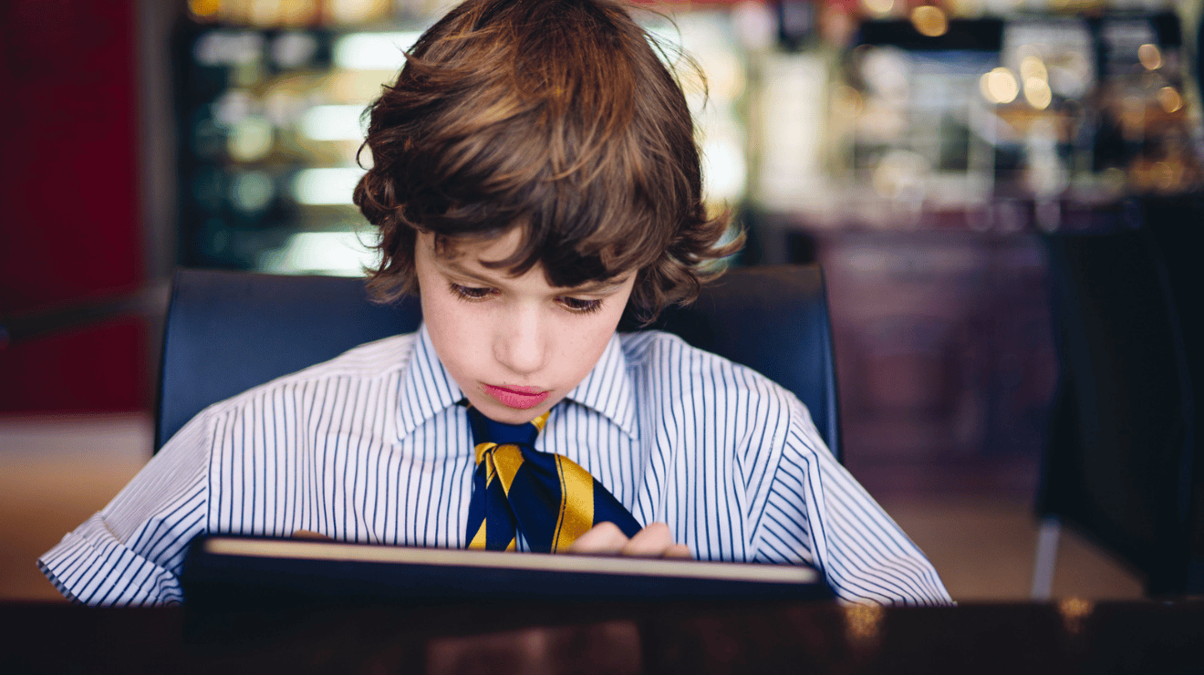 Image of young boy in school uniform looking at computer screen