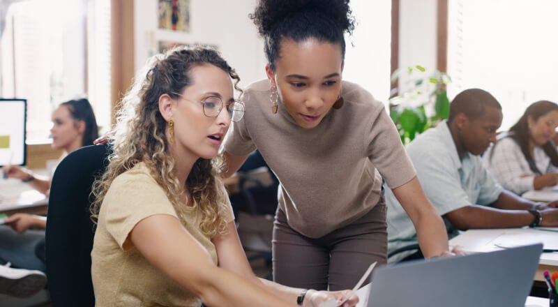 A teacher helping a student on a laptop
