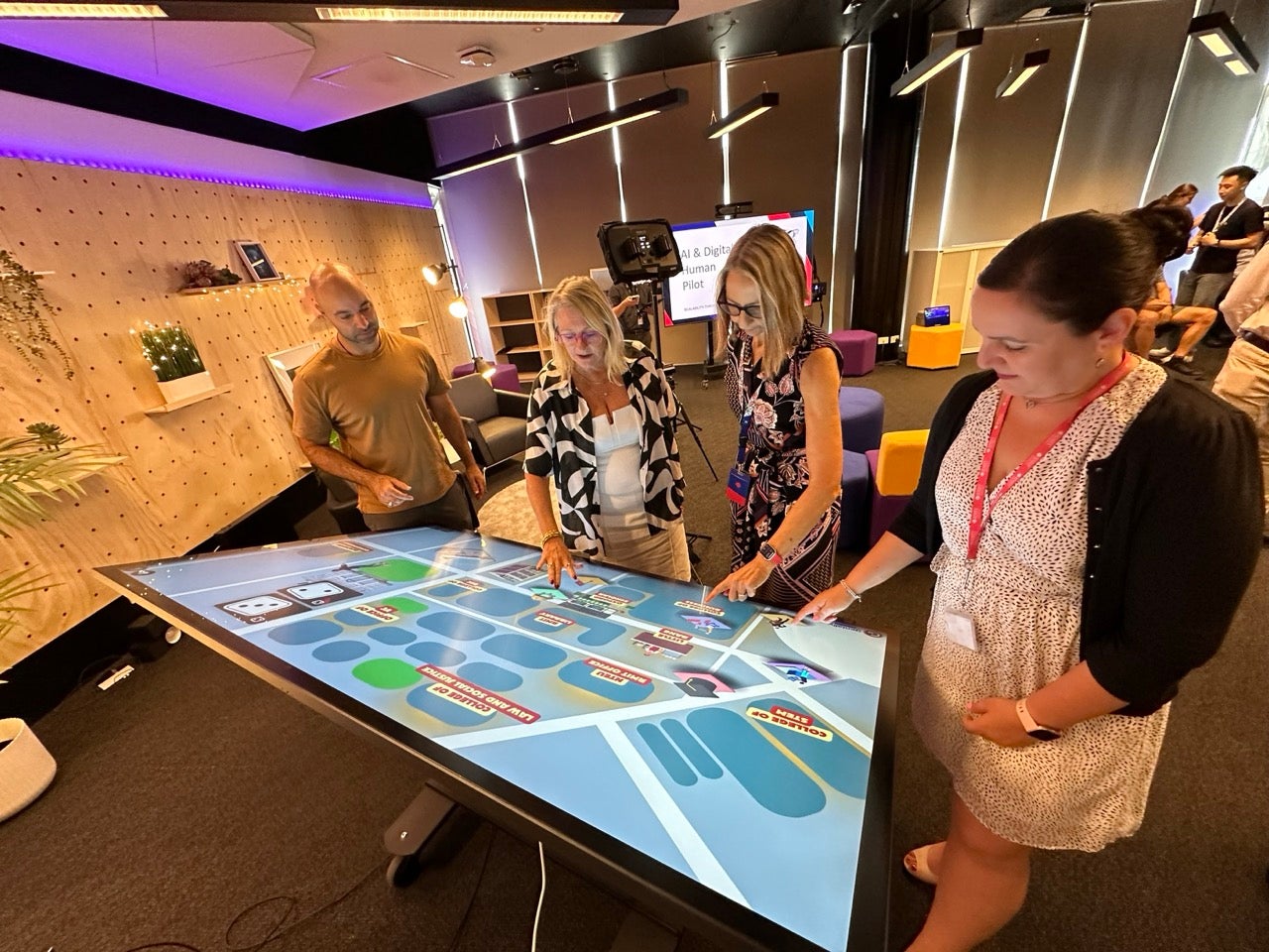 Student and teachers around a touch screen, interacting with an illustration of a map.
