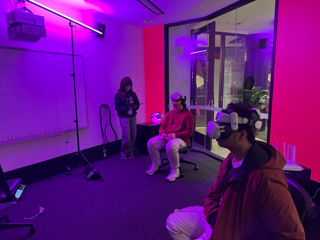two students sitting down in an room, wearing VR goggles and doing a simulation.