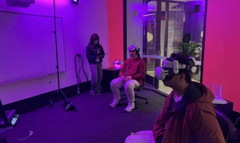 Student and teachers around a touch screen, interacting with an illustration of a map.