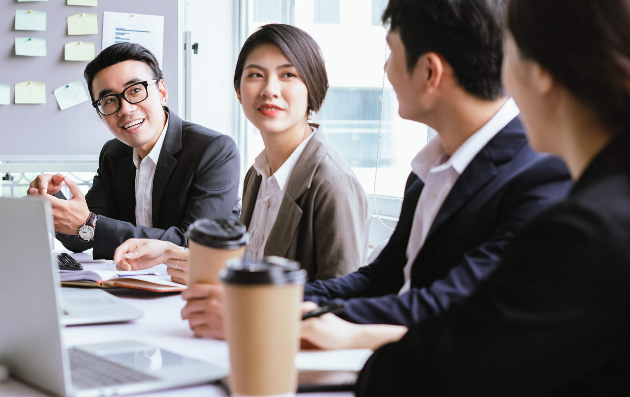 Four co-workers chatting and smiling at a conference table