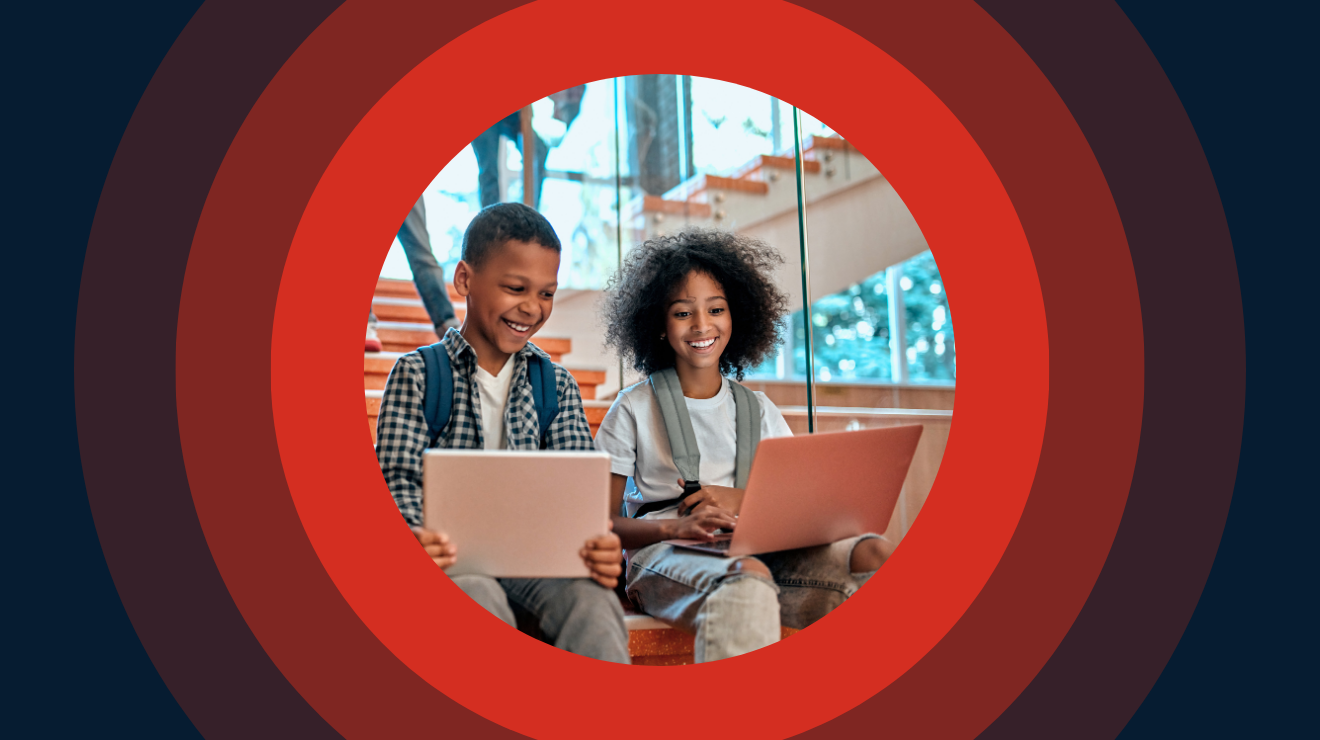 two students sit at laptops, smiling