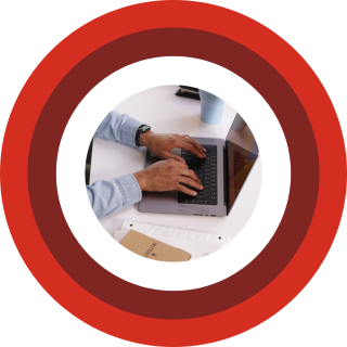 Image of a mans hands typing on his keyboard, centered on red and maroon concentric rings.