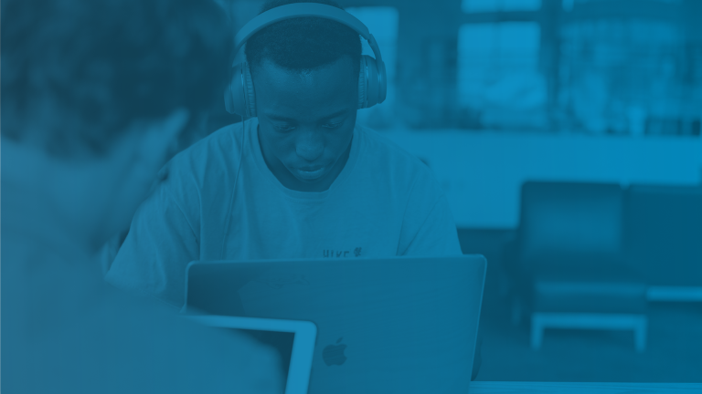 Teenage boy with headphones on studying at a laptop.