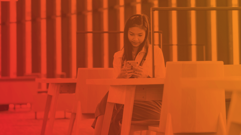 girl looks at her phone while sitting at a desk