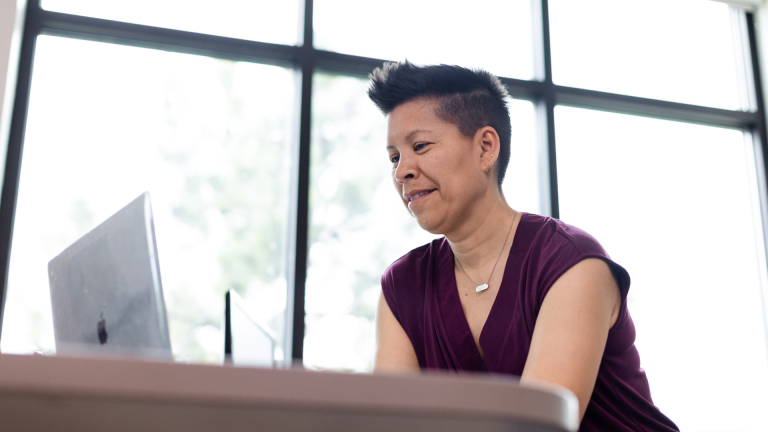 woman in purple shirt smiling at computer