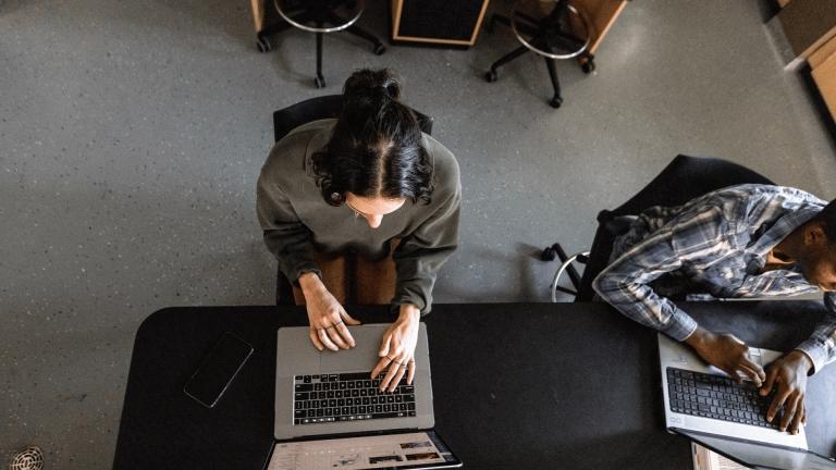aerial overhead image of girl in green sweater typing on laptop
