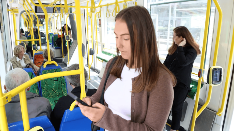 Maddi Rose on a Melbourne tram looking at Canvas on her mobile