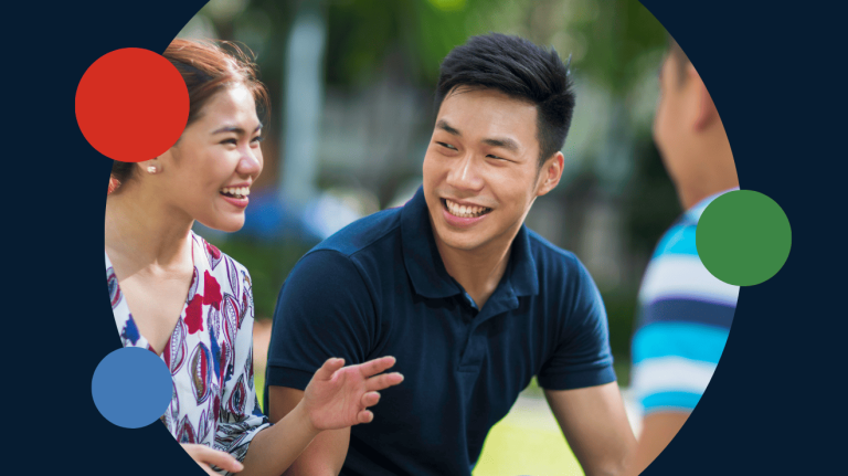 A man and woman engage in conversation, surrounded by a group of people.