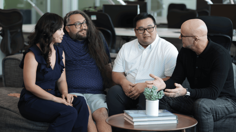 Four people sitting on a couch, engaged in a conversation 