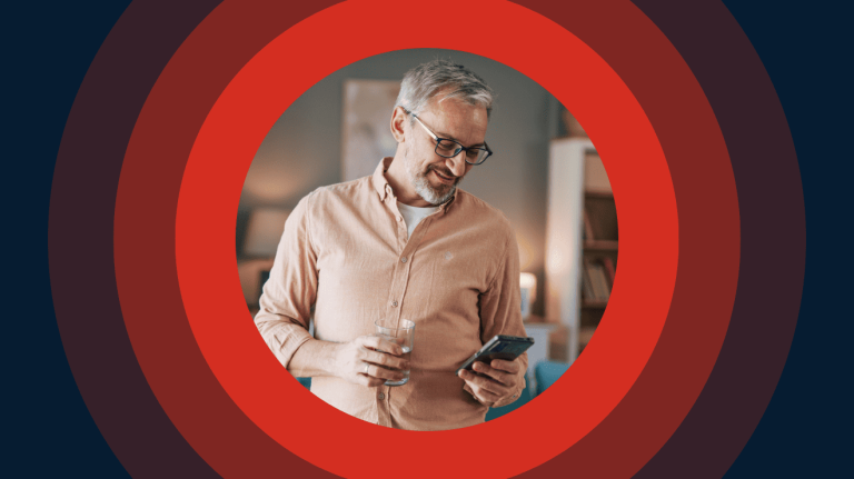 A man with glasses interacts with a phone, set against a vivid red circle backdrop