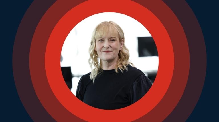 Woman smiling confidently in a modern office, centered within red concentric circles representing focus and connection.