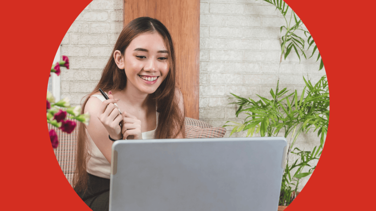A woman smiling while working on a laptop, conveying a sense of joy and engagement in her task.