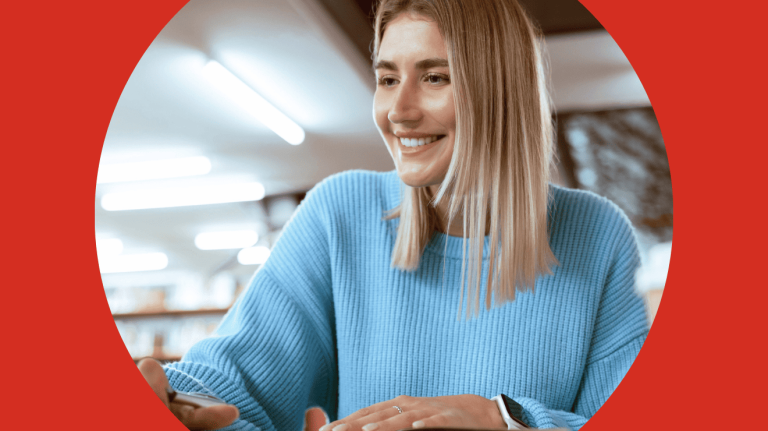 A woman smiles while working on her laptop, conveying a sense of joy and engagement in her task.