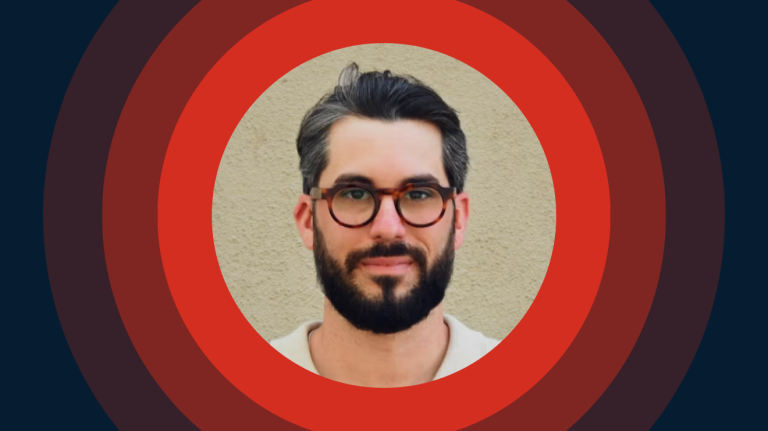 A man with glasses and a beard with red circles as a background.