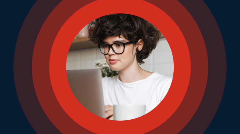 A woman with glasses is looking at her laptop