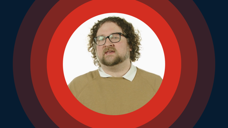 A man with glasses and a beard is centered within a red and blue circular design.