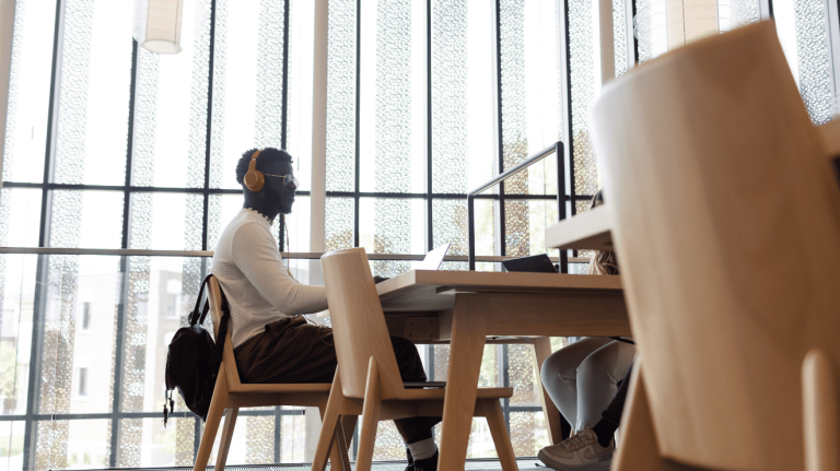 A person at a table using a laptop, surrounded by a simple, uncluttered environment.