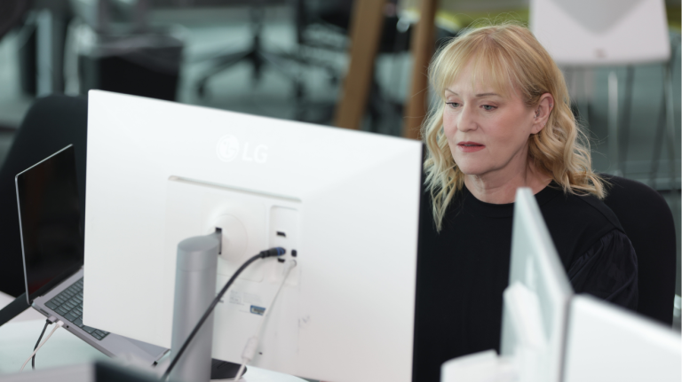 A woman seated at a desk, focused on her work at a computer screen.