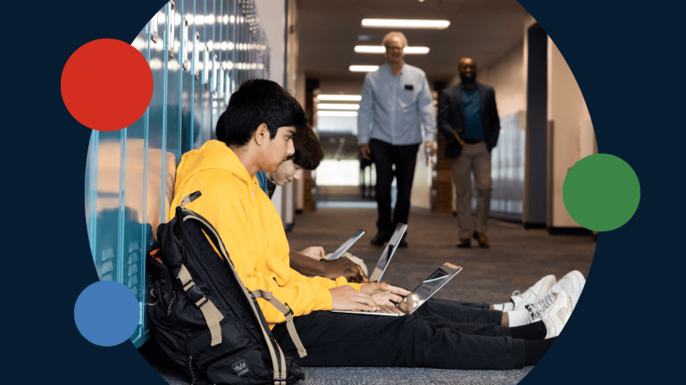 Two students sitting on the floor, focused on their laptops, engaged in a collaborative study session.