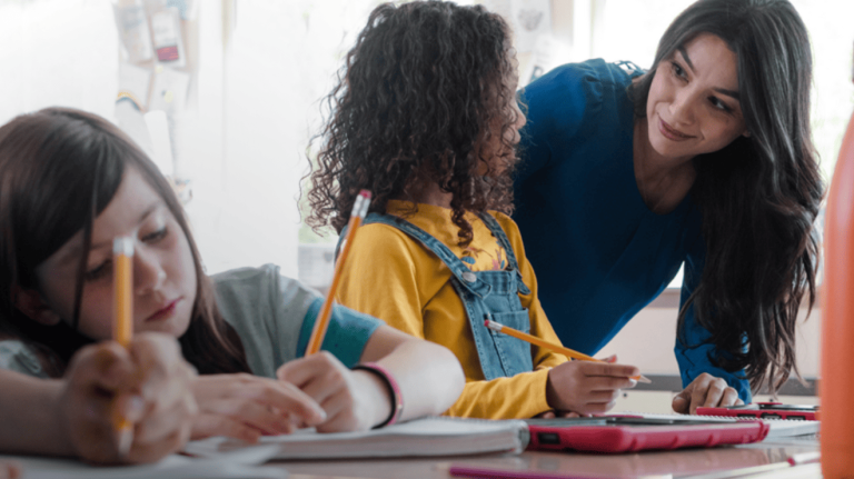 A woman assists children with their homework at a table, providing guidance and support in their learning process.
