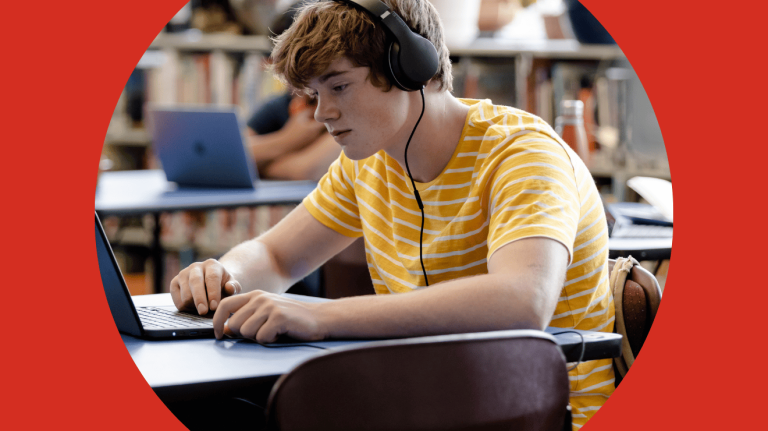 A young man using a laptop while wearing headphones