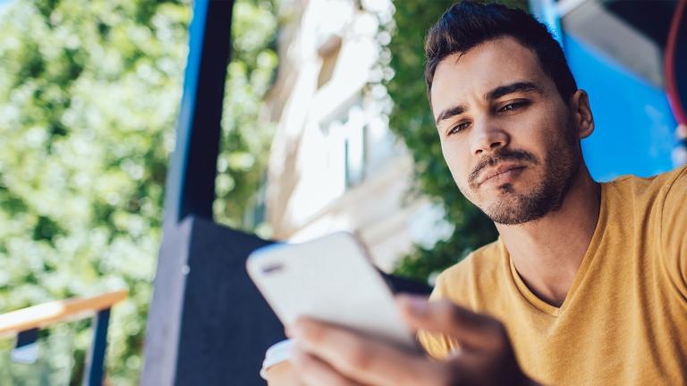 Man views phone app while sitting down outside