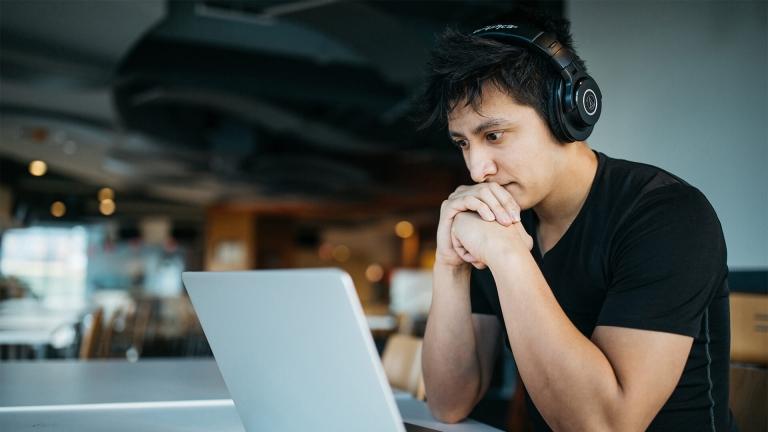 Man studies laptop screen with intent