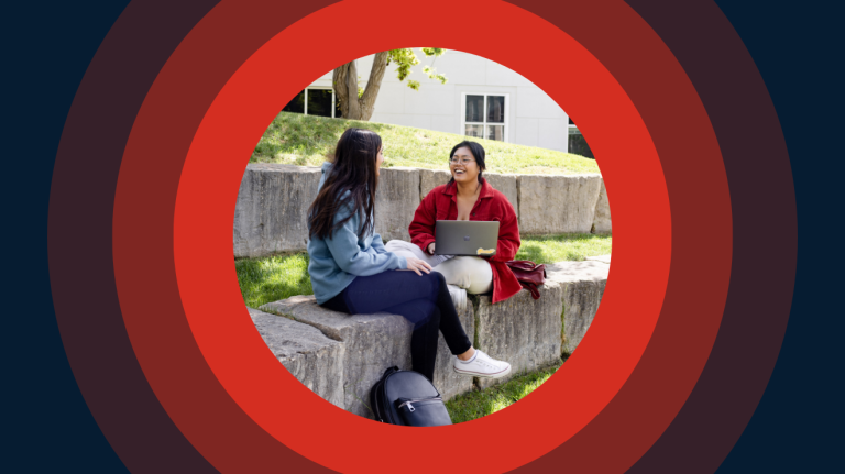 Two people sit on stone steps outdoors, smiling and talking while one uses a laptop. The scene is framed by concentric red and dark blue circular graphics.