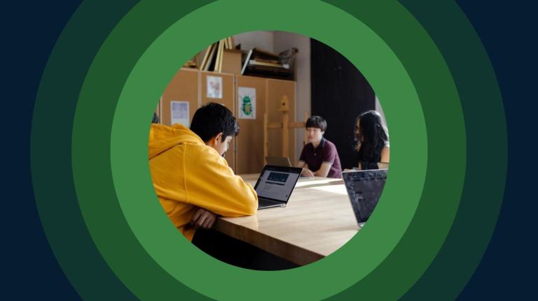 students sit at a table in a high school classroom